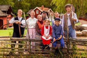 Familjen Svensson samlad vid Katthult, med gården i bakgrunden, en del av Astrid Lindgrens Värld, en autentisk miljö från Emil i Lönneberga.